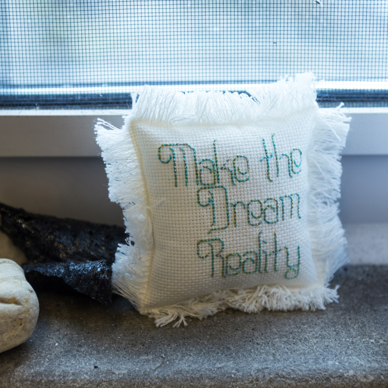 A pillow with "Make the Dream Reality" on it